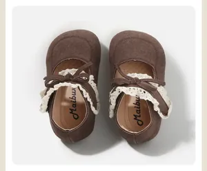 Close-up of brown baby Mary Jane shoes with white lace trim and bowknot details