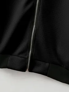 Macro view of black waffle knit texture and metallic zipper on a men's zip-up jacket