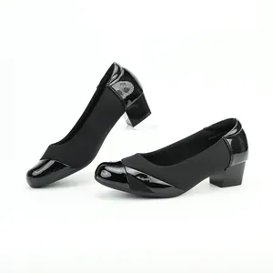 Detail view of black block heel pumps featuring glossy patent toe and matte finish.