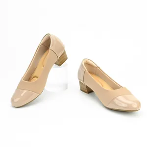 Detail view of stylish beige mid block heel pumps with elegant patent leather cap toe