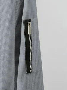 Macro detail of high-quality metal zipper on a gray waffle knit men's jacket sleeve