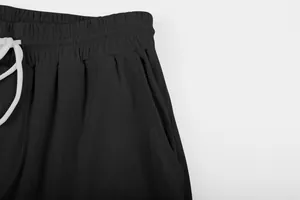 Close-up of black corduroy trousers showing elastic waistband and white drawstring