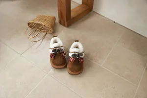 Close-up of cute girls' brown snow boots with cherry decorations and bow detail