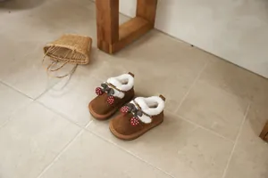 Close-up of brown girls snow boots featuring cute cherry decorations and warm plush lining.