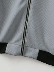 Close-up of grey waffle knit jacket showing silver zipper and black ribbed hem detail
