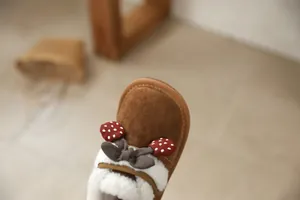 Close-up detail of the cute cherry and bow decor on girls' brown winter faux fur snow boots