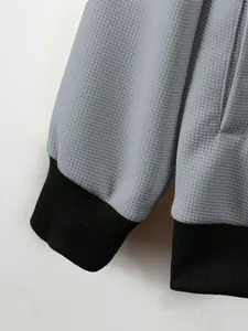 Detailed view of grey waffle knit texture and black ribbed cuffs on a men jacket.