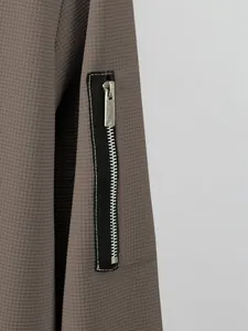 Close-up showing the metallic zipper pocket on a men's brown waffle knit cardigan sleeve