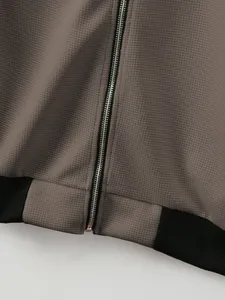Close-up detail showing the silver zipper and waffle knit texture of a men's grey jacket