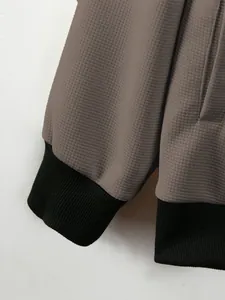 Detail view of men's waffle knit jacket with black ribbed cuffs and taupe fabric