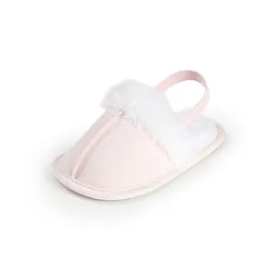 Detalle de zapatilla de peluche rosa para bebé con adorno de pelo sintético y elástico.