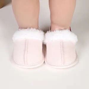 Vista detallada de zapatillas rosas para bebé con ribete de pelo blanco para invierno.