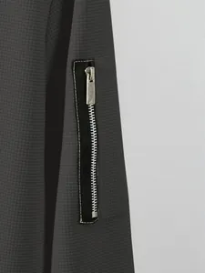 Close-up detail of the silver zipper pocket on a dark grey waffle knit men's jacket