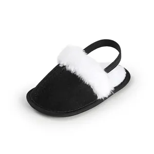 Primer plano de una zapatilla de casa negra para bebé con pelo blanco y correa elástica