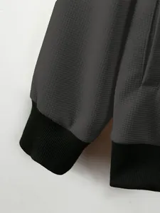 Detailed close-up of men's waffle knit jacket showing fabric texture and black ribbed cuffs.