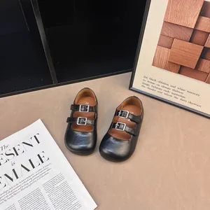 Scarpe Mary Jane nere retrò per bambina con cinturini a doppia fibbia su sfondo neutro.