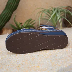 Dettaglio della suola marrone antiscivolo di sandali con zeppa blu stile romano donna