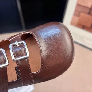Dettaglio di scarpe Mary Jane vintage marroni a punta tonda con doppie fibbie.
