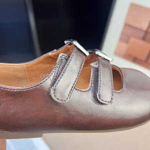 Dettaglio di scarpe Mary Jane marrone metallizzato per bambine con doppi cinturini.