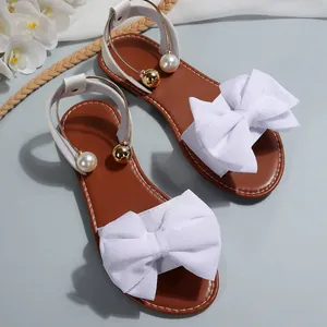 Gros plan sur le nœud en tissu blanc et la décoration en perles de sandales plates pour femmes