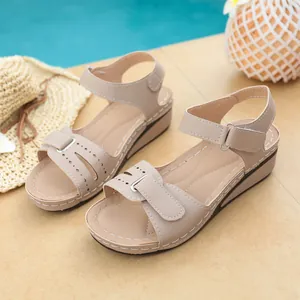 Vista dettagliata e ravvicinata dei sandali con zeppa beige e cinturini velcro