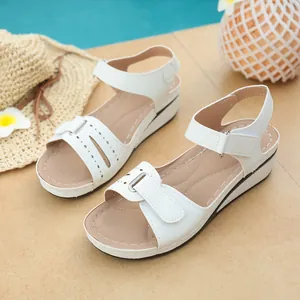 Dettaglio di sandali con zeppa bianchi da donna con intagli decorativi e chiusura velcro