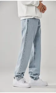 Side detail view of men's loose straight-leg jeans in light blue wash denim fabric