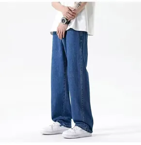 Detail view of men's loose wide-leg straight-cut blue denim jeans on a model.
