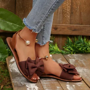 Sandales plates en daim marron avec nœuds surdimensionnés et perles décoratives à la cheville