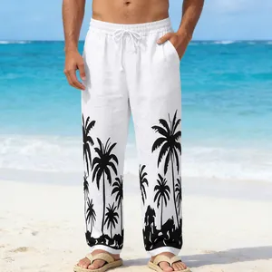 Detail view of men's white beach trousers with black palm tree prints on a tropical shore