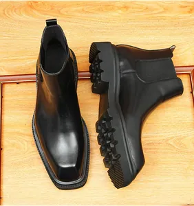 Detailopname van zwarte glanzende leren Chelsea boots met dikke profielzolen.