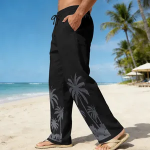 Men's stylish black beach trousers with grey palm tree print in a sunny coastal setting