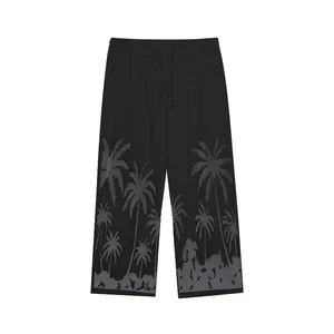 Detail view of men's casual black beach trousers featuring grey palm tree prints.