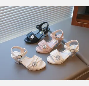 Gruppenausstellung von Mädchensandalen mit Strassblumen in den Farben Schwarz, Rosa und Beige.