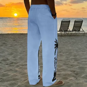 Rear view of light blue men's beach pants with black palm tree side prints at sunset