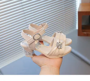 Detail der cremefarbenen Mädchen-Sandalen mit glitzernder Strassblume und Mondanhänger.