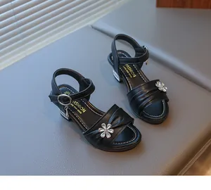 Detailansicht eleganter schwarzer Mädchensandalen mit glitzernder Strassblume.