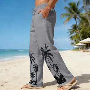 Detail of men's gray beach trousers featuring black palm tree print on a sunny beach.