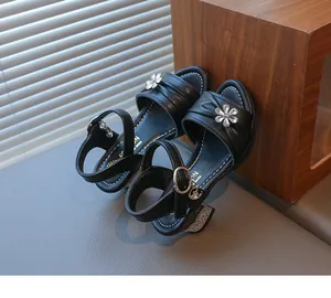 Detailaufnahme der schwarzen Mädchen-Sandalen mit funkelnder Kristallblumen-Dekoration.