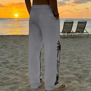 Back view of men's grey casual beach trousers with black palm tree prints at sunset beach