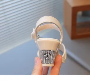 Detailansicht der glitzernden Strassblume an weißen Mädchen-Sandalen mit Absatz