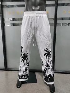 Detailed view of men's white beach pants with black palm tree print and drawstring