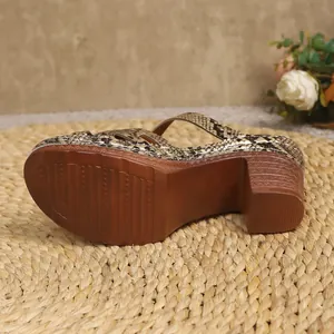 Detail view showing the non-slip brown sole and thick high heel of snake-print sandals