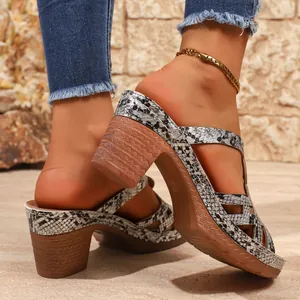 Detailed view of snake print platform high-heeled Roman sandals worn by a model outdoors.