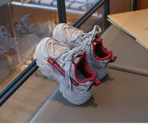 Gros plan de baskets en maille grise pour enfants avec accents rouges et semelle.