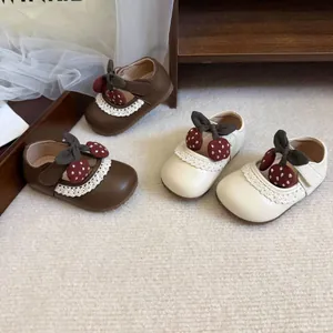 Close-up of baby girl Mary Jane shoes with lace trim and cute strawberry bow details