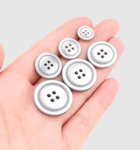 Close-up of various sized silver resin buttons held in a hand for scale