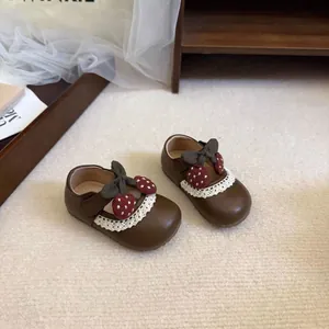 Detail view of brown toddler girl princess shoes with lace trim and cute cherry bow ornament