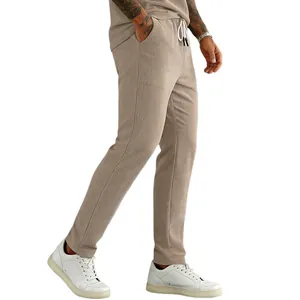 Detail view of stylish men's beige corduroy drawstring pants worn with white sneakers.