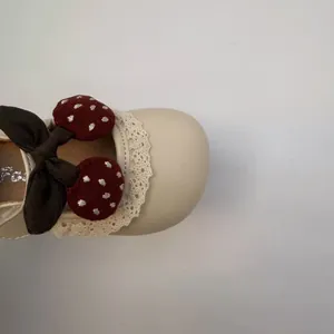 Detail of beige baby girl princess shoe with lace trim and embroidered cherry charm
